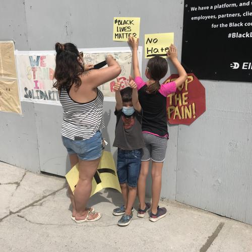 Community members posting black lives matter and no hate signage
