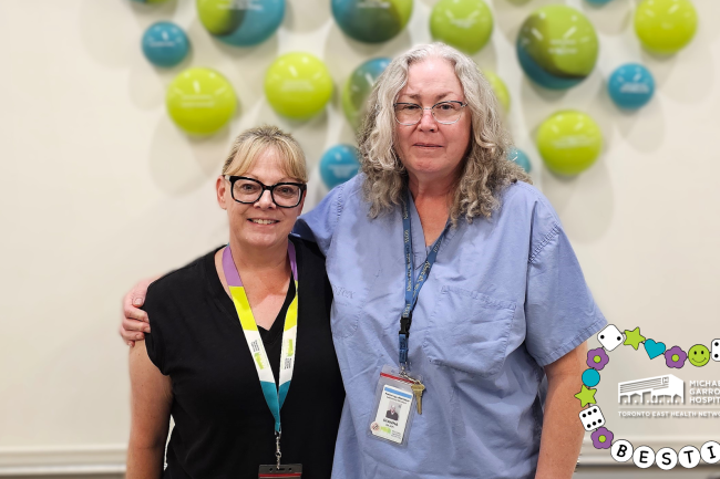 Two people stand in a hospital hallway and are smiling.  Two people stand in a hospital hallway and are smiling.