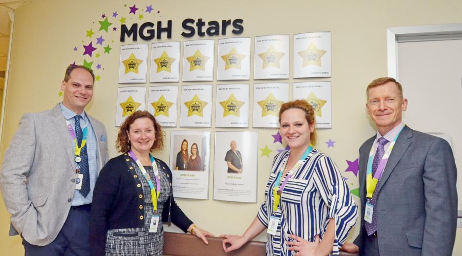Wolf and colleagues standing in front of a display that says "MGH Stars" at the hospital.