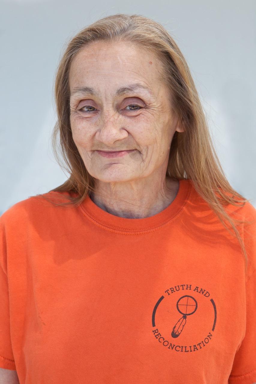 A woman wearing an orange shirt and smiling.