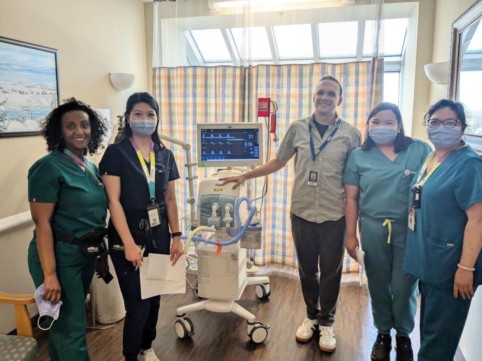 Healthcare workers standing beside a new mechanical ventilator. Healthcare workers standing beside a new mechanical ventilator.
